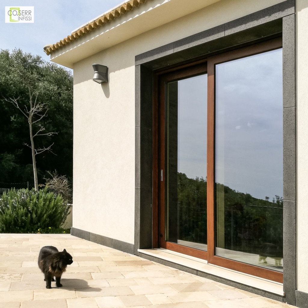 Porta alzante scorrevole in alluminio effetto legno Domal installata in una villa ad Augusta con gatto nero