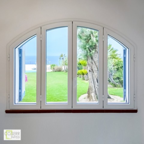 Finestra ad arco in allumnio con quattro ante di colore bianco con vista su mare e giardino di villa di pregio ad Augusta