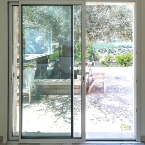 Porta scorrevole bianca in alluminio con guide incassate a pavimento in villa di campagna ad Augusta